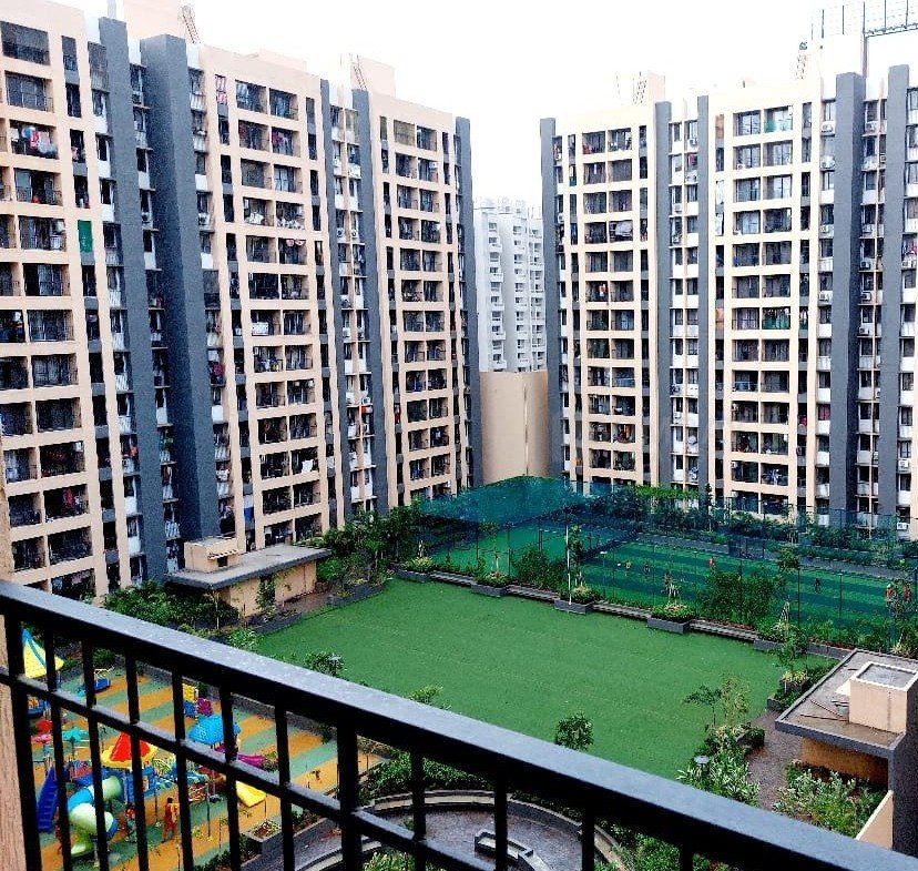 Balcony view of residential towers with landscaped courtyard and sports court